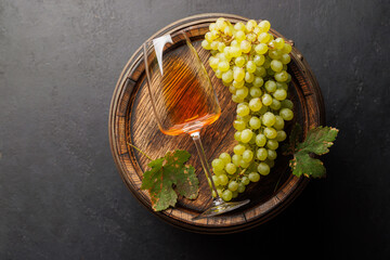 Naklejka premium Rose wine glass and green grapes on a wooden barrel