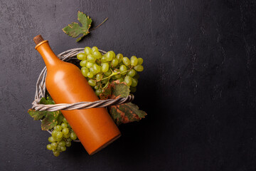 Naklejka premium Terracotta wine bottle and green grapes in a wicker basket