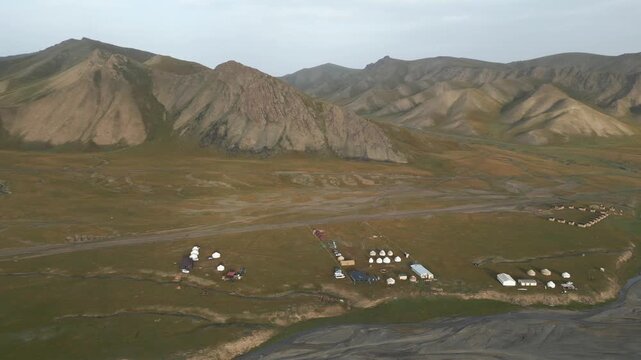 Stunning aerial footage capturing a traditional yurt camp situated by a river in the mountainous Kok Kiya Valley of Kyrgyzstan