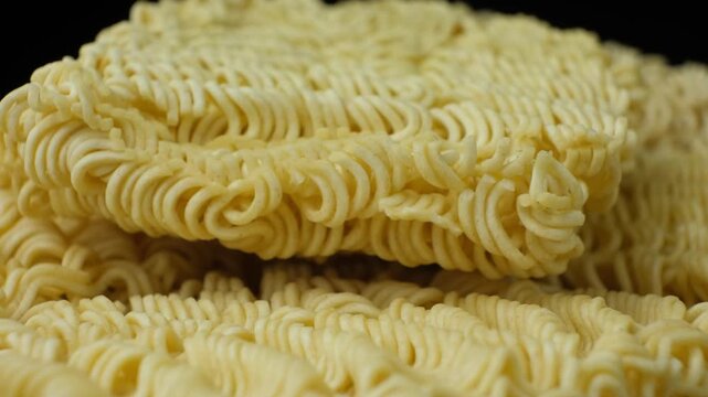 Extreme close up of yellow wavy dry noodles spinning slowly