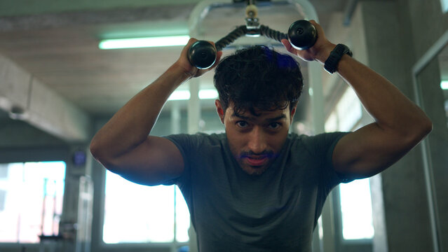 Athletic man performing a cable rope exercise to build upper body strength in a modern fitness center