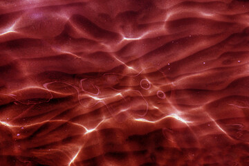 Surreal mars like red water ripples with glowing abstract sun caustics © gelog67