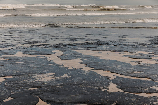 Oil fuel contamination spreads across a beach, creating a serious environmental pollution disaster
