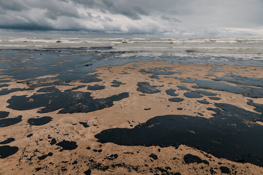 Extensive oil pollution along a sandy coastline, illustrating marine environmental damage and crisis