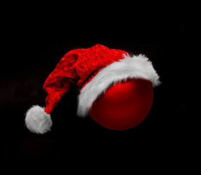 Weihnachtsm&uuml;tze und Weihnachtskugel vor dunklem Hintergrund