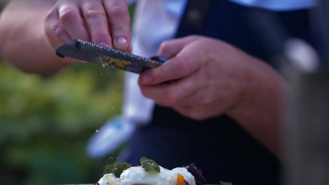 Chef sprinkles fresh parmesan over a gourmet dessert plating
