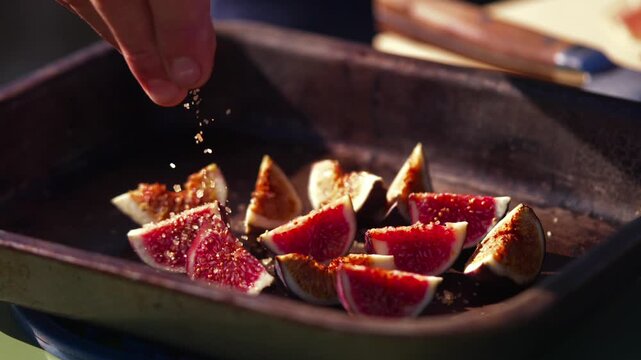Grilled fig halves are seasoned with spices on a rustic metal tray