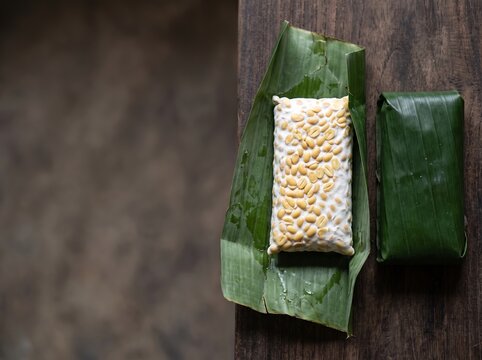 Block of tempeh wrapped in banana leaf on wooden table