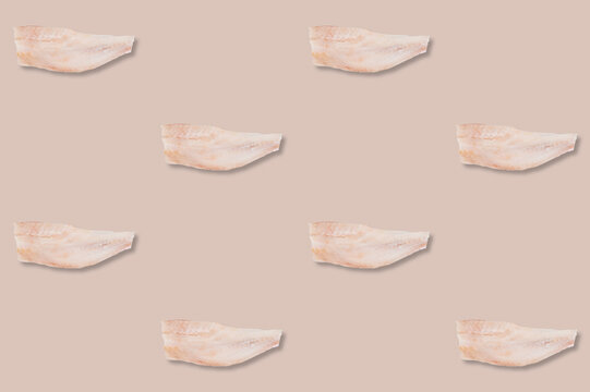 Repeating pattern of pale raw ocean perch fillets arranged in staggered rows across a soft muted pink background