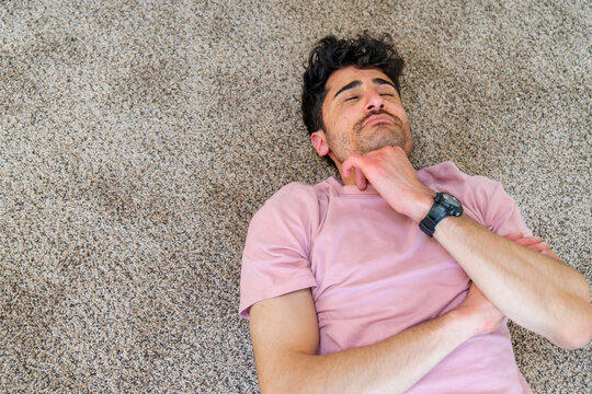 tired man lying down on floor eyes closed thinking