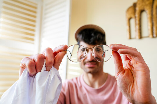 man inspecting eyeglasses cleaning cloth