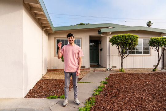 Happy homeowner portrait Moving in showing keys in front of house