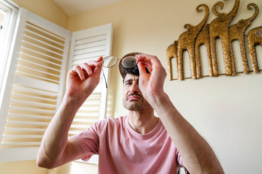 man checking eyeglasses cleanliness lenses