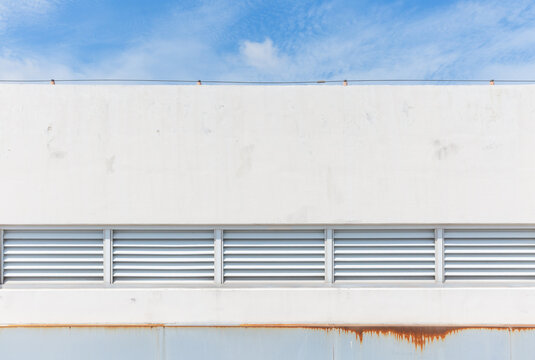 White Building Wall with Louver Vent and Shadow Under Blue Sky