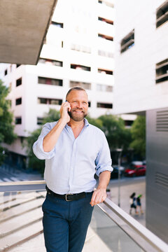 Mature man talking on smartphone on city balcony