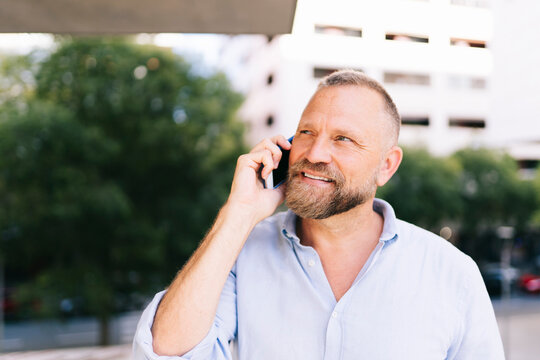 Bearded man smiling making phone call outdoors