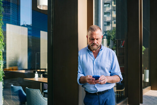 Man checking smartphone outside modern city building