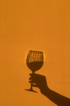 Wine glass shadow silhouette with light refraction on warm background