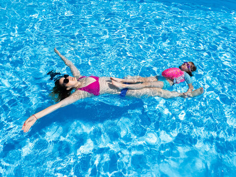 Mother and daughter float in the pool together.