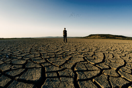 Man walking in barren land due to climate change