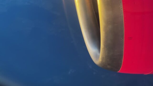Plane jet engine is seen in the air with the sunset, sunrise sun shining on it. The sun is reflecting off the engine, creating a beautiful and serene scene