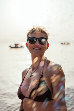 smiling woman among soap bubbles on a greek beach