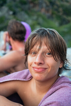 smiling young man wrapped in a towel after swimming
