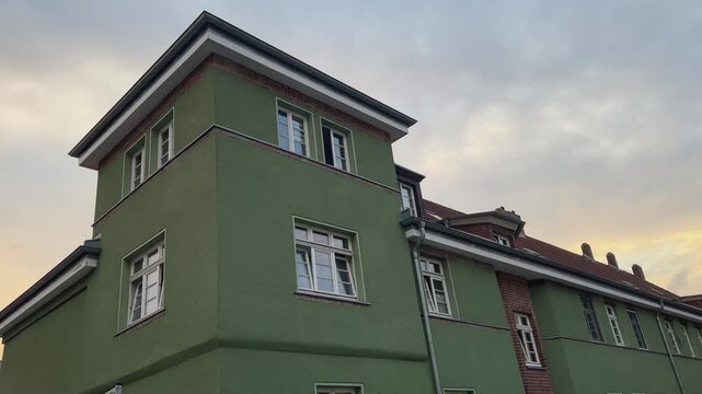 Germany establishing shot ot tradigional neigbourhood green building with many windows. The building is tall and has a red roof