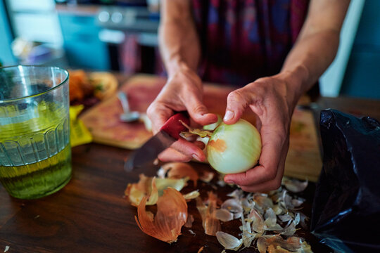 Hands Peeling a White Onion Over a Kitchen Counter