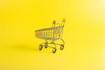 Rear view of yellow miniature shopping cart on yellow background. Concept for retail ecommerce online shopping and consumerism.  © wibiwisnu