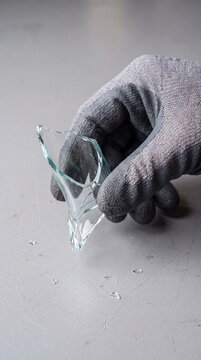Gloved Hand Picking Up Sharp Glass Shard Safely.