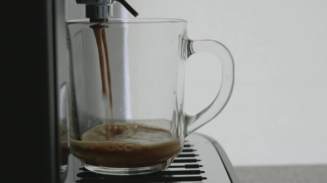 Freshly brewed coffee pouring into a transparent cup