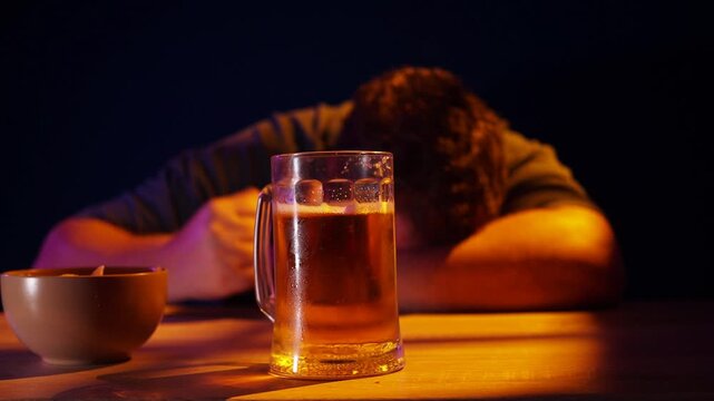 Depressed  man sitting at a kitchen counter with a beer mug, struggling with alcohol addiction and mental health issues