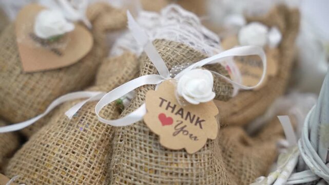 Charming rustic style burlap favor bags featuring printed thank you tags arranged perfectly on a table setup ready to be gifted to guests as a token of appreciation at the wedding reception.