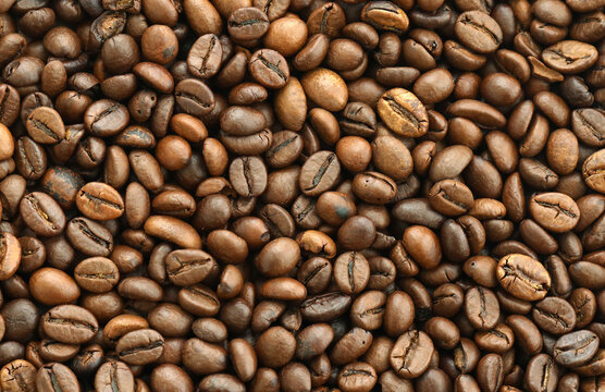 Detailed view on brown roasted coffee beans in big pile on table close up