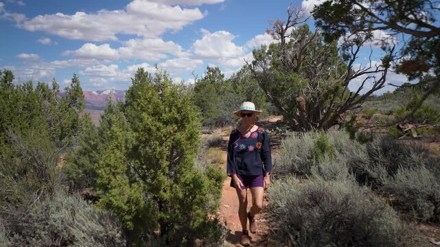 A pretty senior woman explores the Gander Trail on Gooseberry Mesa, taking in stunning sights of Zion National Park in Utah.