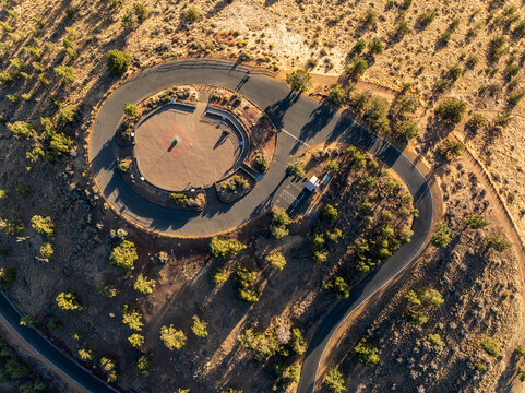 An aerial perspective of the summit loop and parking area at Pilot Butte State Scenic Viewpoint in Bend Oregon featuring high desert terrain.
