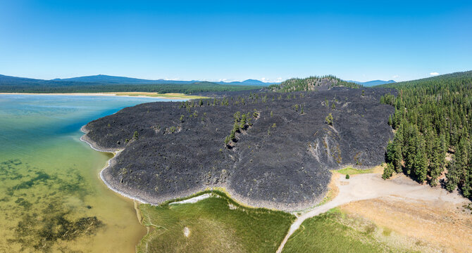 Aerial view of a dark basalt lava flow entering the clear waters of Davis Lake in Deschutes County Oregon USA
