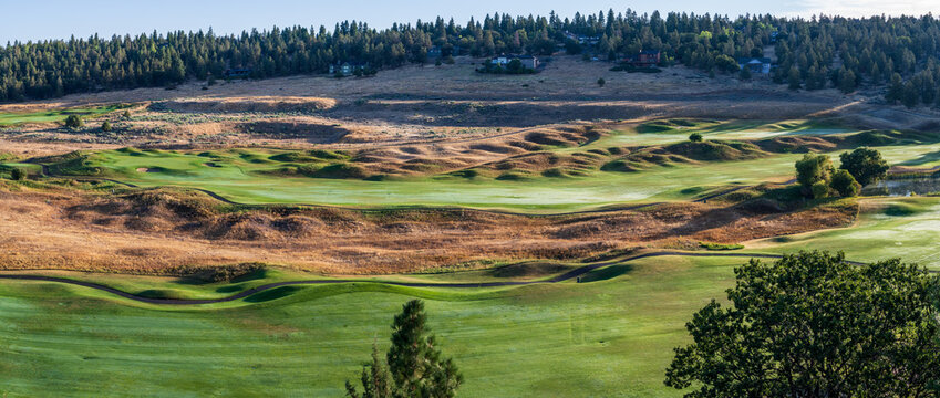 Manicured fairways of a golf course meet natural grasslands and a distant lake framed by forested mountains in Klamath Falls Oregon.