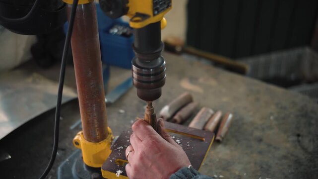 Close-up of a knife maker's hands drilling holes into knife handles in his workshop. Concept of knife making, craftsmanship, precision manufacturing, metalworking, artisanal production, skilled manual