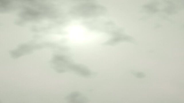 Abstract cloudy sky video background with soft glowing sun shining through diffuse mist and hazy clouds, minimalist serene ambient light texture