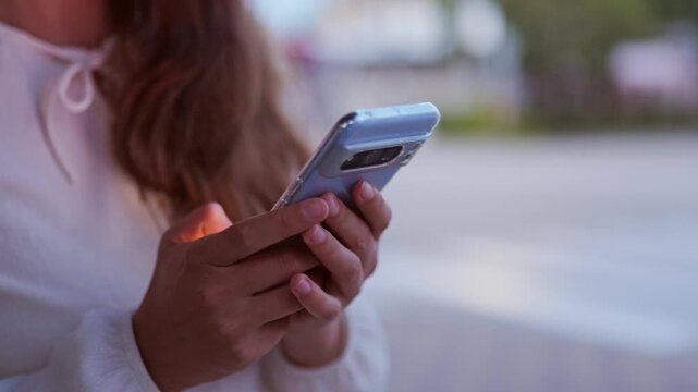 Close up of woman hands holding modern smartphone with camera bar outdoors in evening light