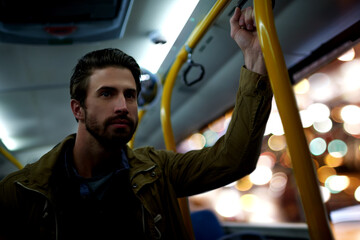 Man, travel and night with bus for public transportation, local commute or trip in city. Male person, traveler or passenger with handle rail in vehicle for late evening ride or journey downtown © peopleimages.com