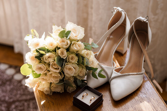 Bride white rose bouquet with elegant heels and gold rings