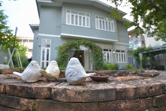 Plaster bird figurine on the edge of the pond in front of house
