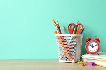 Pencil holder with stationery and red alarm on table, closeup. © Sunlight