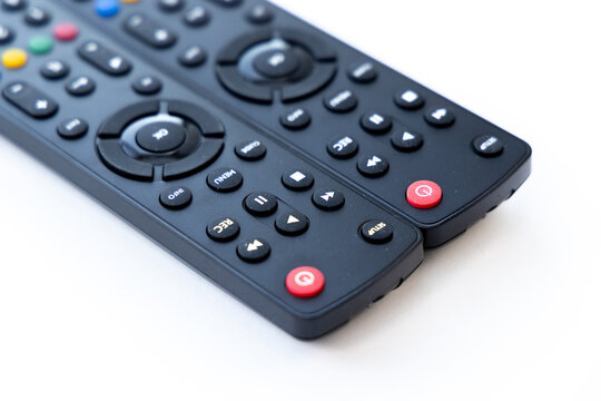 Two modern black remote controls on white background