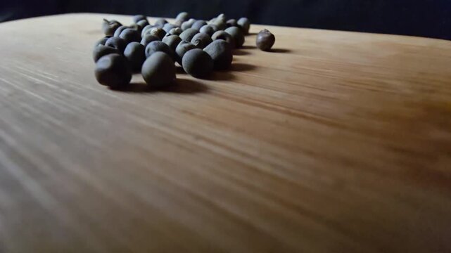 Close-up of dried okra seeds scattered on a clean wooden board, showcasing natural textures and earthy tones for agricultural, culinary, and botanical projects.   