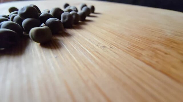 Extreme close-up macro video of dried okra seeds on a wooden board, showcasing detailed textures and natural organic tones with a shallow depth of field for agricultural themes.   