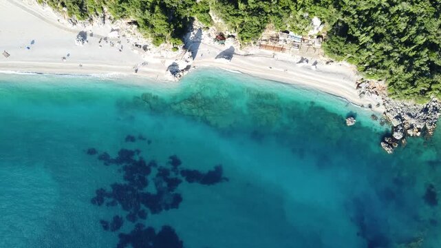 Scenic pebble beach with turquoise waters, aerial drone view. Beautiful white stone beach and crystal clear turquoise sea in Dhermi, southern Albania.